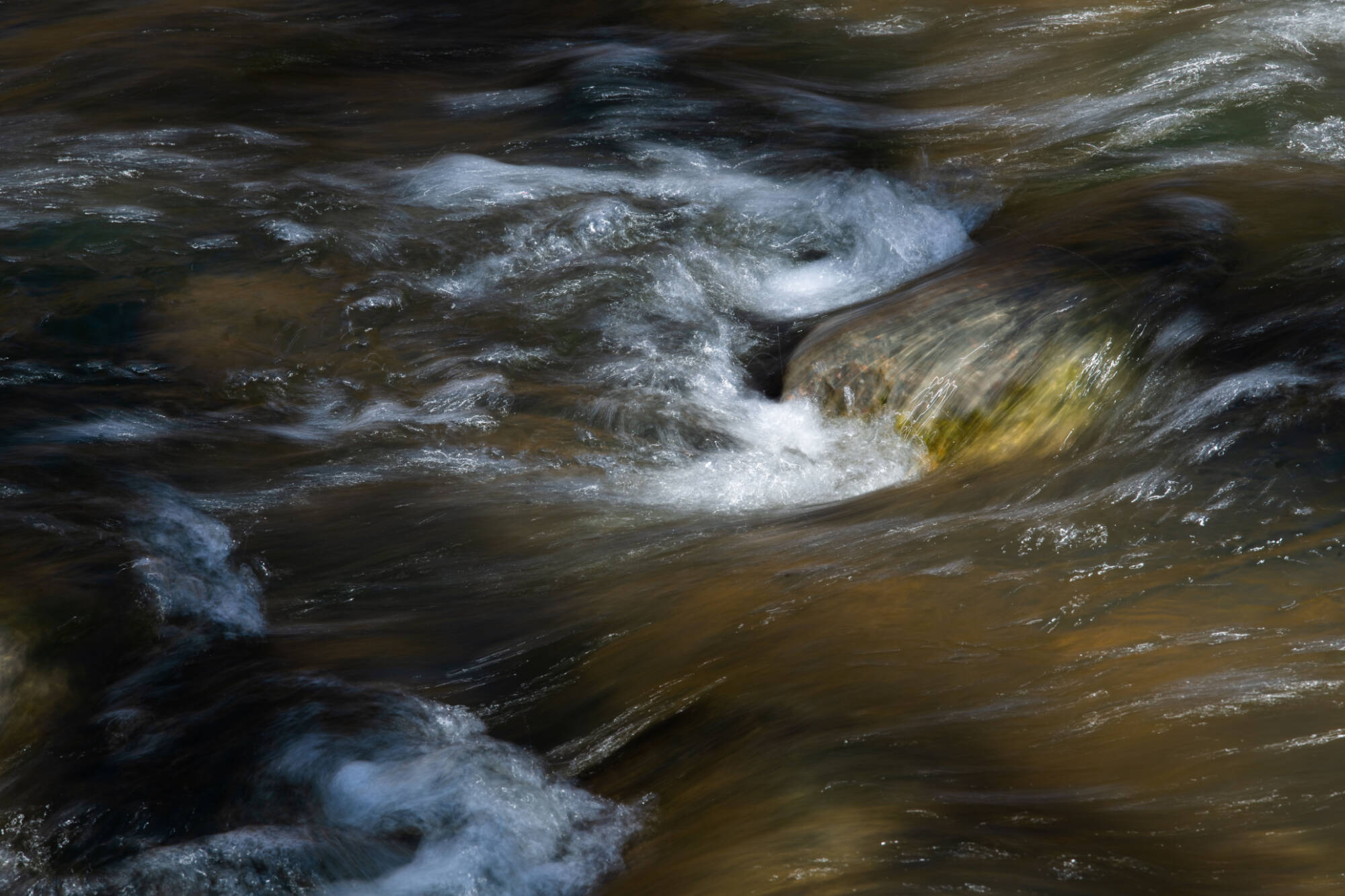 close up of river water rushing over rocks to create small rapids